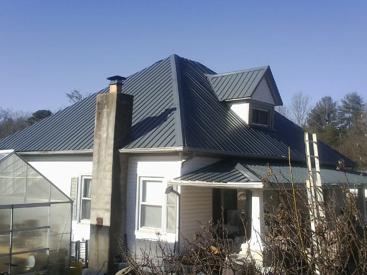 Dark blue standing seam metal roof on a white farmhouse with dormer — Slate & Tile Roof Repair by Roofing Brothers in Munster