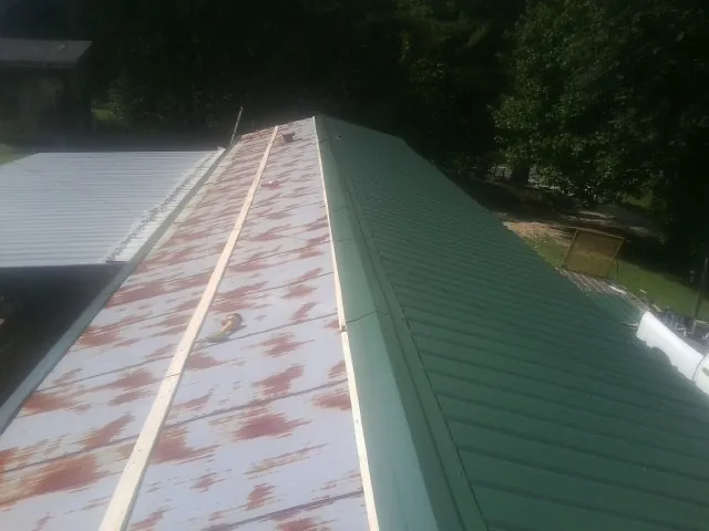 Old rusted panels beside newly installed green metal roofing — Wind Damage Roof Repair by Roofing Brothers in Munster