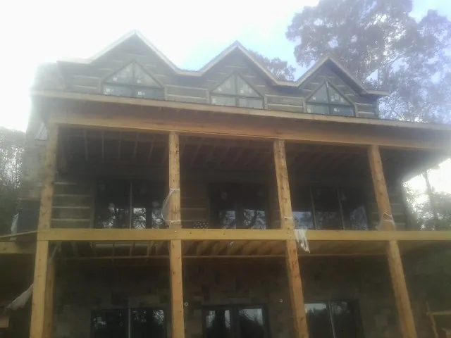 Dormers and porch framing on a large log home under construction — Roof Coating work by our crew in Munster