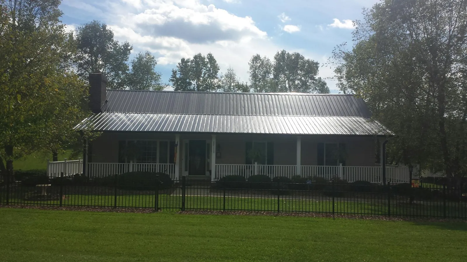 Gray metal roof on a brick ranch with a full width front porch — Gutter Guard Installation work by our crew in Munster