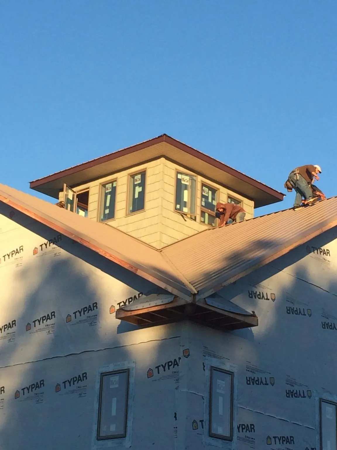Roofers working around a rooftop cupola on a new metal roof at sunset — Roof Waterproofing in Munster by Roofing Brothers